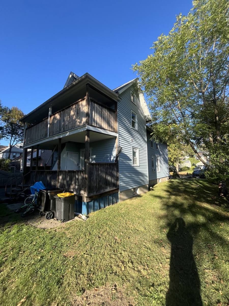 Blue two-family house with porches on both floors on the East Side of Binghamton, NY, on a sunny fall day