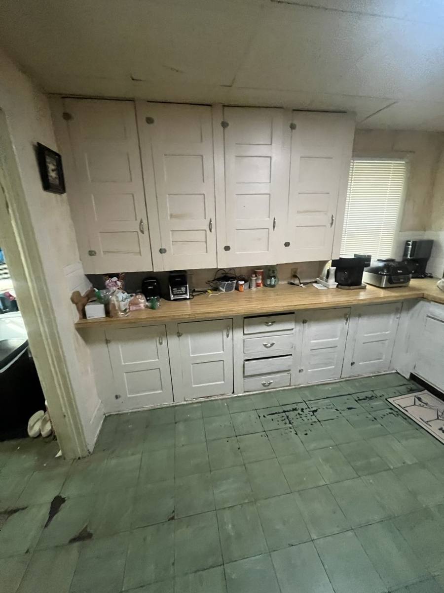 Original kitchen with painted cabinets and worn floor